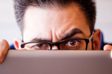 hacker scammer worried user looking over laptop