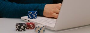 white laptop with gambling chips and hands