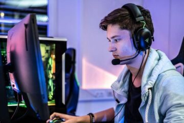 young adult gaming in front or computer with headset